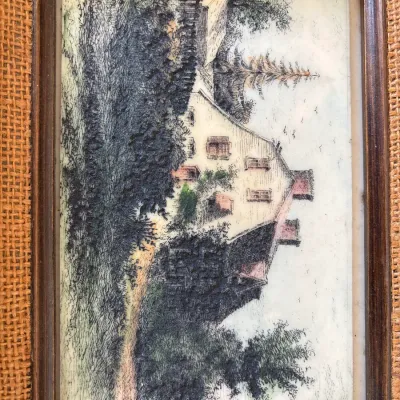 Framed etching of a countryside estate nestled among trees, presented in a dark wood frame with a woven burlap outer border.