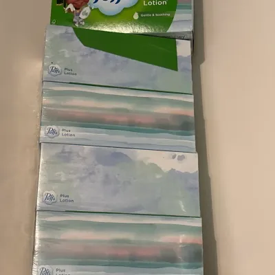 Stack of Puffs Plus Lotion facial tissue boxes, new and unopened.