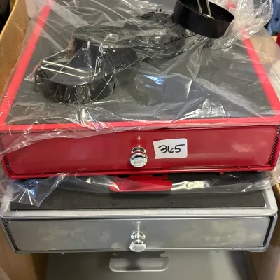 Stack of metallic single-drawer office organizers, featuring a red unit in plastic wrap on top with accessories and a lot tag numbered 365.
