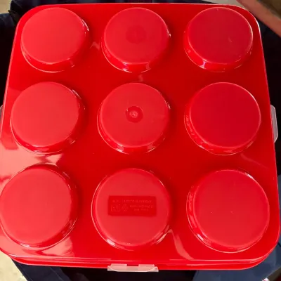 Red plastic storage container with a nine-compartment modular lid design, shown in clean condition.