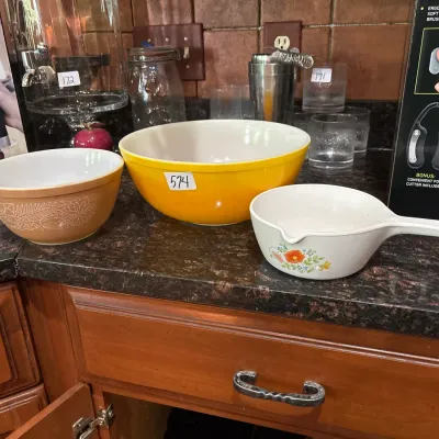 Vintage Pyrex and CorningWare kitchenware set, including a tan floral Pyrex mixing bowl, a bright yellow Pyrex bowl, and a floral...