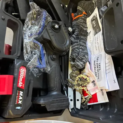 Portable cordless mini chainsaw kit inside a hard plastic carrying case, complete with 2000mAh lithium battery, power adapter, spare...