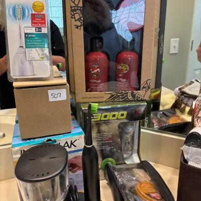 Collection of personal care items, including an Ed Hardy gift set, Philips Sonicare toothbrush heads, a dental water flosser, and a shoe...