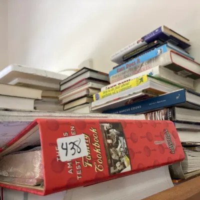 Large collection of cookbooks and instructional books in hardcover and binder formats, including The America's Test Kitchen Family...