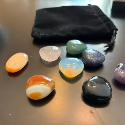 Collection of eight polished heart-shaped and oval gemstone cabochons, including agate, quartz, and opalite, with a black velvet storage...
