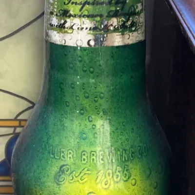 Vintage Miller Chill beer bottle display featuring Chelada style branding with lime and salt details, showing some wear to the paper label.