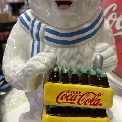 Vintage Coca-Cola polar bear ceramic cookie jar featuring the bear with a striped scarf holding a stack of soda crates.