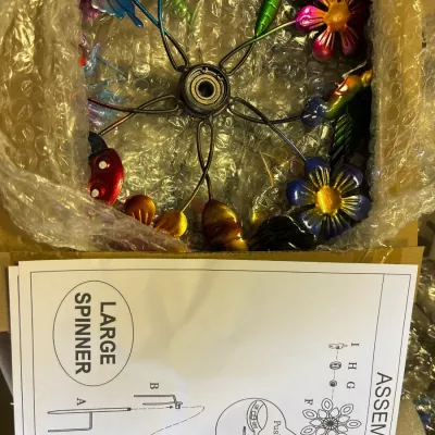 Unassembled colorful metal garden wind spinner, packed in original box with assembly instructions included.