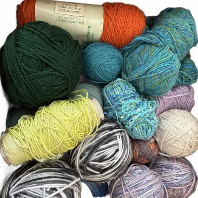 Assorted collection of yarn skeins and wound balls in various colors and textures, including acrylic and wool blends.