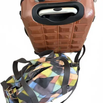 Rose gold hardside rolling suitcase paired with a colorful geometric fabric duffel bag.