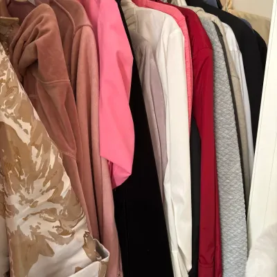 Collection of women's outerwear, hoodies, and jackets hanging in a closet, featuring a mix of colorful and patterned styles.