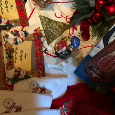 Collection of Christmas decor items, including embroidered hand towels, festive picture frames, ceramic figurines, and artificial...