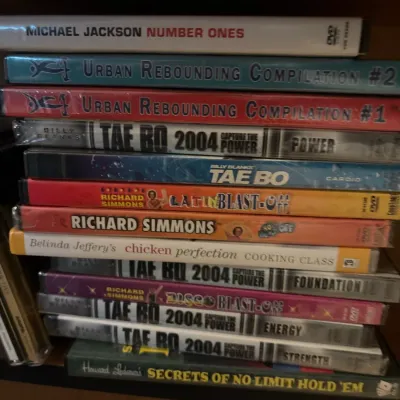 Stack of vintage DVDs and books, including Billy Blanks Tae Bo, Richard Simmons fitness videos, and Michael Jackson Number Ones.