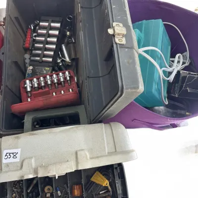 Plastic toolboxes filled with assorted hand tools, socket sets, bits, and hardware alongside a purple fabric storage tote containing...