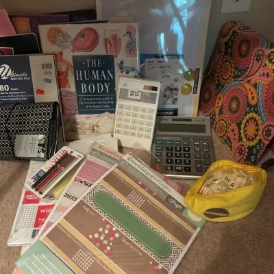 Assortment of office and stationery supplies, including notebooks, calculators, paper, envelope wraps, a human body reference book, and a...