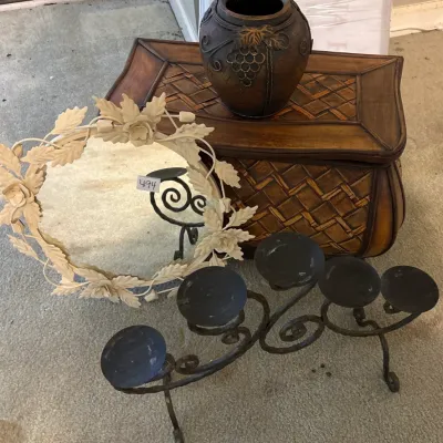 Collection of home decor items including a white floral-framed mirror, a black wrought iron multi-candle holder, a ceramic jar with grape...