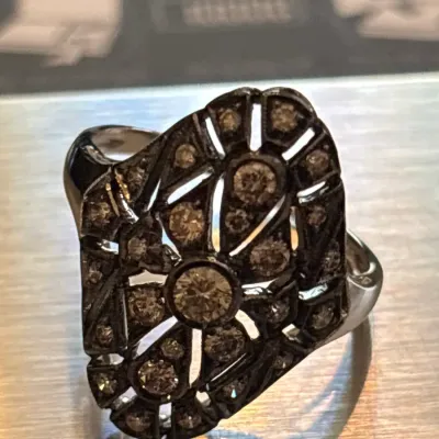Art Deco style diamond cocktail ring featuring an intricate filigree setting with multiple round-cut accent stones.