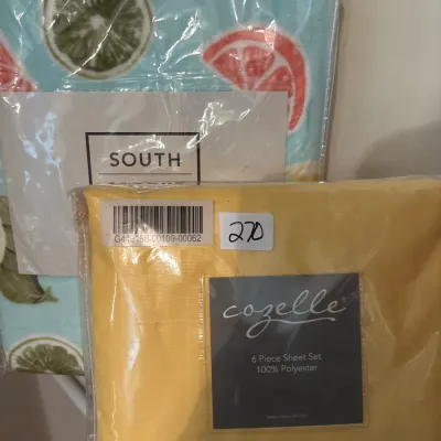 Two packaged bedding sets, including a yellow Cozelle 6-piece 100% polyester sheet set and a light blue citrus-printed item.
