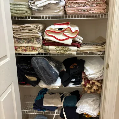 A closet filled with organized shelves of folded linens, towels, and various household textiles in a variety of colors and patterns.