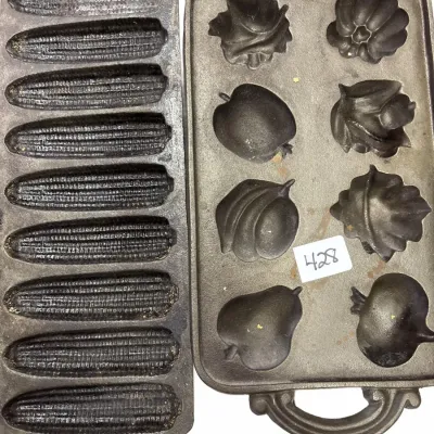 Two vintage cast iron baking pans, including a corn stick pan and a Nordic Ware harvest fruit-shaped muffin pan.