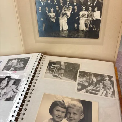 Vintage photo album containing black-and-white family portraits and a framed wedding group photograph, circa mid-20th century.