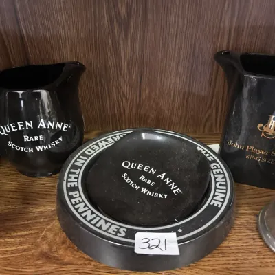Vintage black ceramic pub advertising collectibles including Queen Anne Scotch Whisky and John Player Special water pitchers, along with...