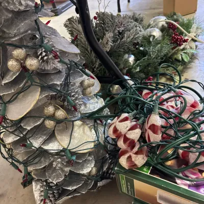 Collection of holiday decorations, including a silver pinecone-style cone tree wrapped in string lights, peppermint-shaped light strands,...