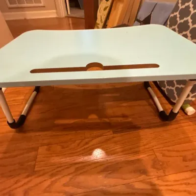 Light blue portable lap desk with foldable metal legs and a built-in tablet slot.