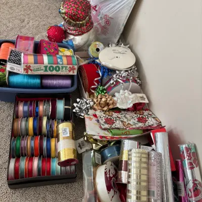 Assortment of gift wrapping supplies, including spools of colorful craft ribbons, rolls of wrapping paper, and decorative bows.