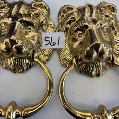 Pair of polished brass lion head door knockers with circular ring handles.