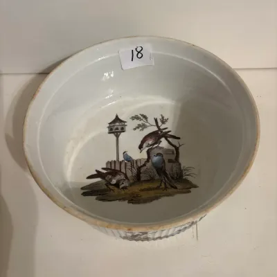 Antique porcelain slop bowl decorated with a hand-colored transferware motif of birds around a birdhouse, featuring a ribbed exterior...
