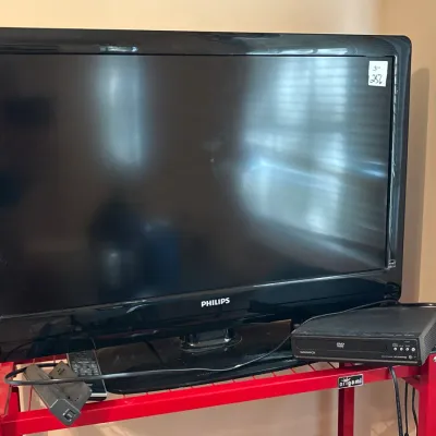 Black Philips flat-screen LCD television paired with a Magnavox DVD player, sitting on a red metal rack.