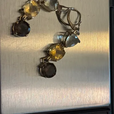 Pair of vintage leverback dangle earrings featuring multi-shaped faceted gemstones in tones of yellow, smoky quartz, and green, displayed...