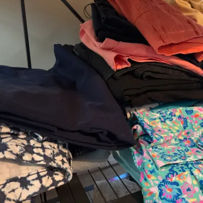 Folded stacks of women's pants and shorts, featuring a variety of solid colors and vibrant floral and tie-dye patterns.