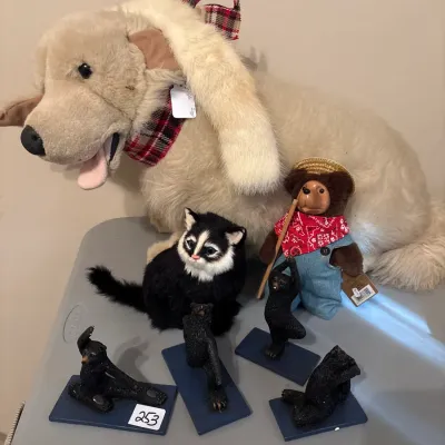 Collection of plush animals including a large stuffed golden retriever, a black and white cat, a teddy bear in overalls, and four small...