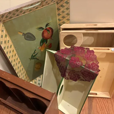 Collection of vintage wooden trays and storage boxes, featuring a large painted tray with fruit and trowel motifs alongside plain wooden...