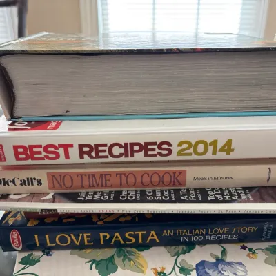 Stack of assorted cookbooks including 'Best Recipes 2014', 'McCall's No Time to Cook', and 'I Love...