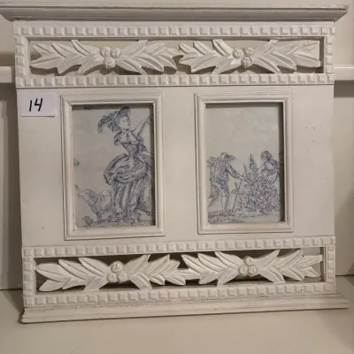French Country-style off-white painted double photo frame featuring carved leaf and ribbon details with two vintage pastoral ink prints.