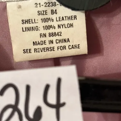 Clothing care tag detailing a size 84 garment with a 100% leather shell and 100% nylon lining, made in China.