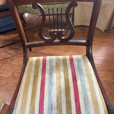 Vintage lyre-back wooden dining chair featuring a striped upholstered seat cushion in red, blue, gold, and cream tones, showing light...