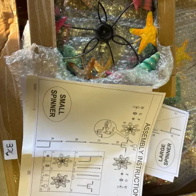 Ocean-themed metal wind spinner featuring starfishes and sea shells, packed in its original box with assembly instructions included.