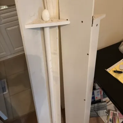 Disassembled white wooden cue rack and shelving pieces leaning against a wall.