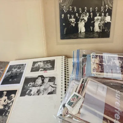 Collection of vintage black-and-white family photographs, including a spiral-bound album, a framed wedding party portrait, and plastic...