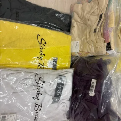 Assortment of new-in-packaging women's clothing, including Slinky Brand tops and bottoms in various colors and sizes.