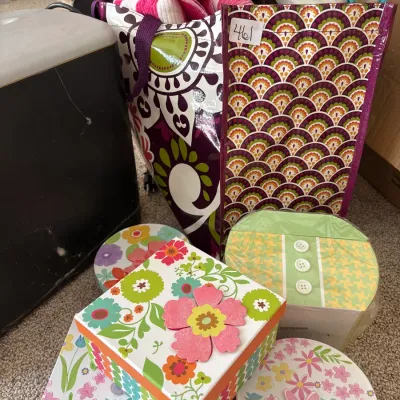 Collection of decorative floral gift boxes and tote bags filled with textiles.