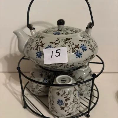Pier 1 Imports ceramic tea set featuring a floral vine pattern, including a teapot with an overhead handle and matching teacups stored on...