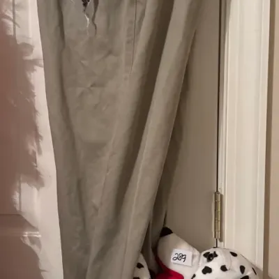 A pair of men's beige khaki trousers paired with a Dalmatian-themed patterned pocket square and a stuffed Dalmatian dog plush.