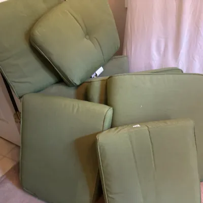Collection of green outdoor furniture cushions stacked against a wall, including seat and back pads.