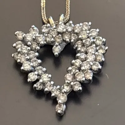 Diamond heart-shaped pendant on a gold snake chain necklace.