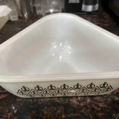 Vintage triangular white milk glass casserole dish featuring a brown geometric crown pattern around the exterior base.